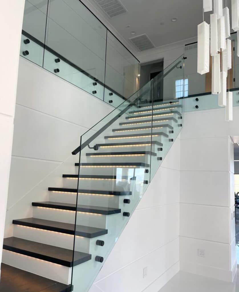 Elegant indoor staircase showcasing a frameless glass railing system with side-mounted hardware