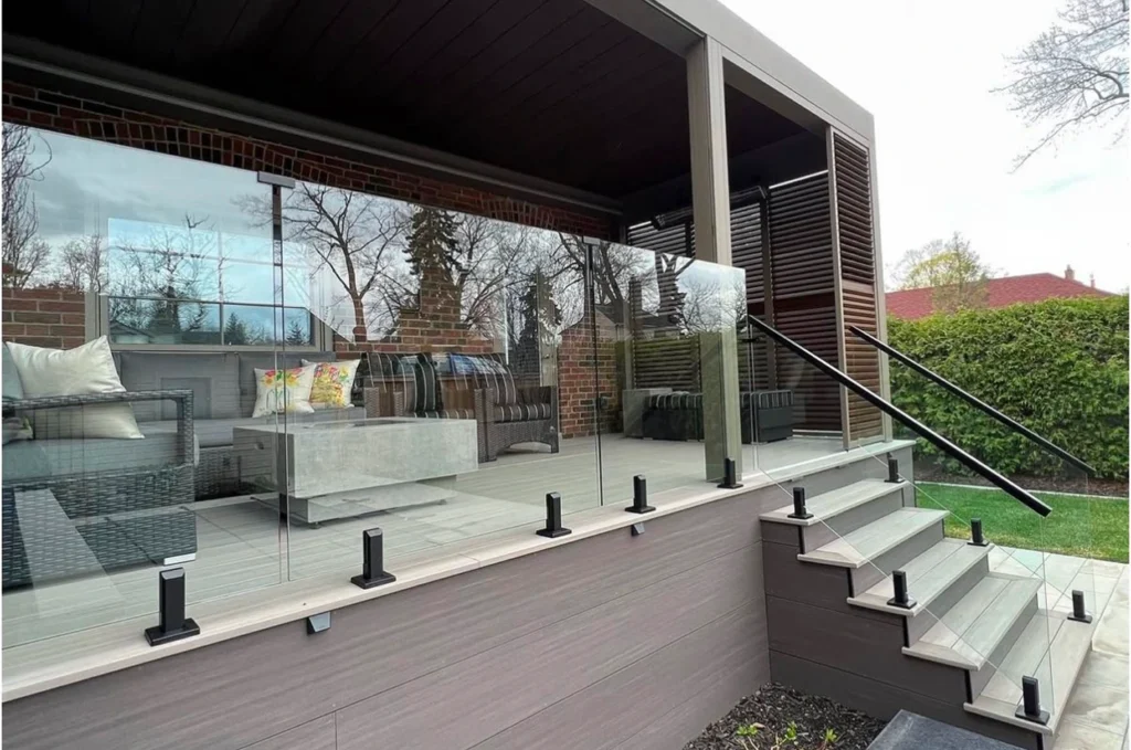 Newly installed custom glass railings on terrace and outdoor stairs of Seattle home with large green yard view