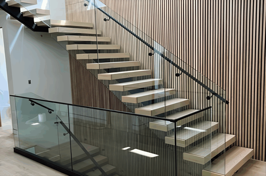Modern floating basement stairs with glass railing and black handrail against wood slat accent wall