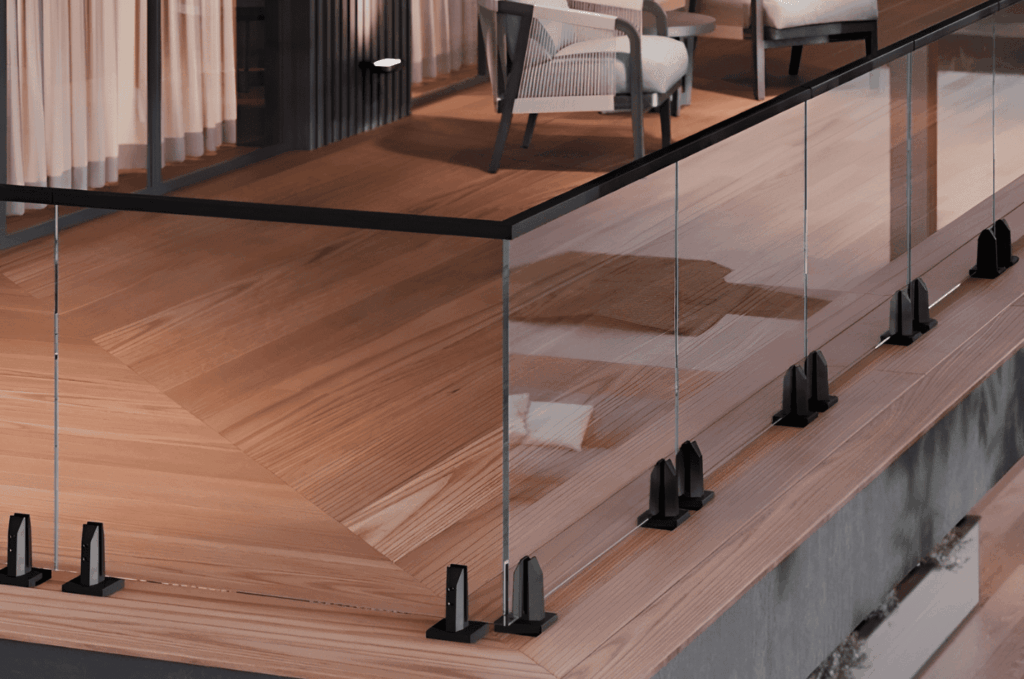 Elegant glass railing hardware featuring black spigot clamps on warm wood flooring