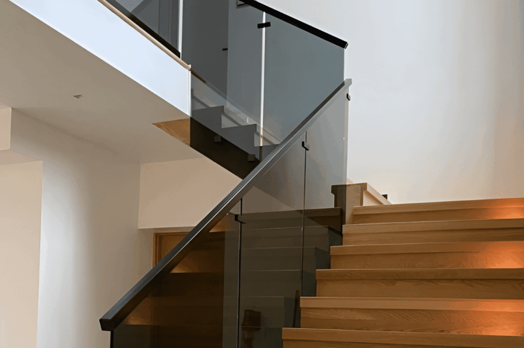 Modern staircase with dark-tinted custom glass railings, creating a sleek custom glass railing interior design