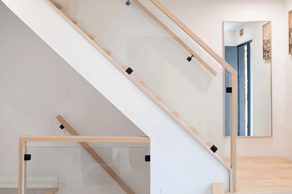  Interior staircase with glass railing hardware framed with natural wood and minimalist black clamp accents