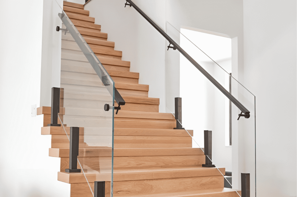 Residential glass railing on modern wooden staircase with black handrail