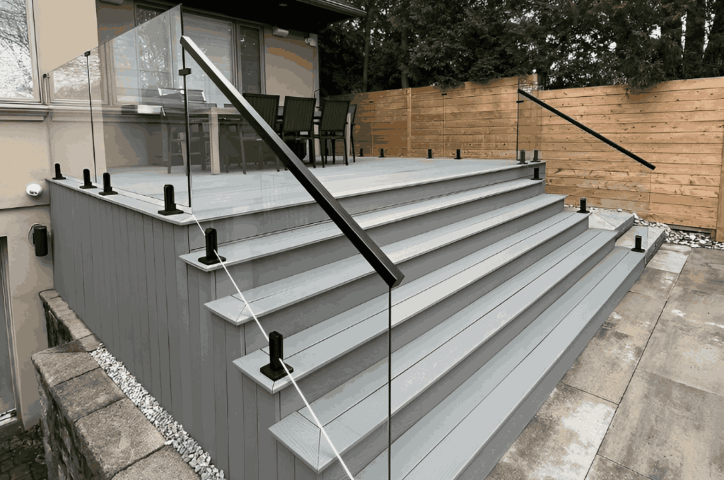 Standoff mounted glass railing on deck stairs, showing base-mounted posts and modern handrail installation