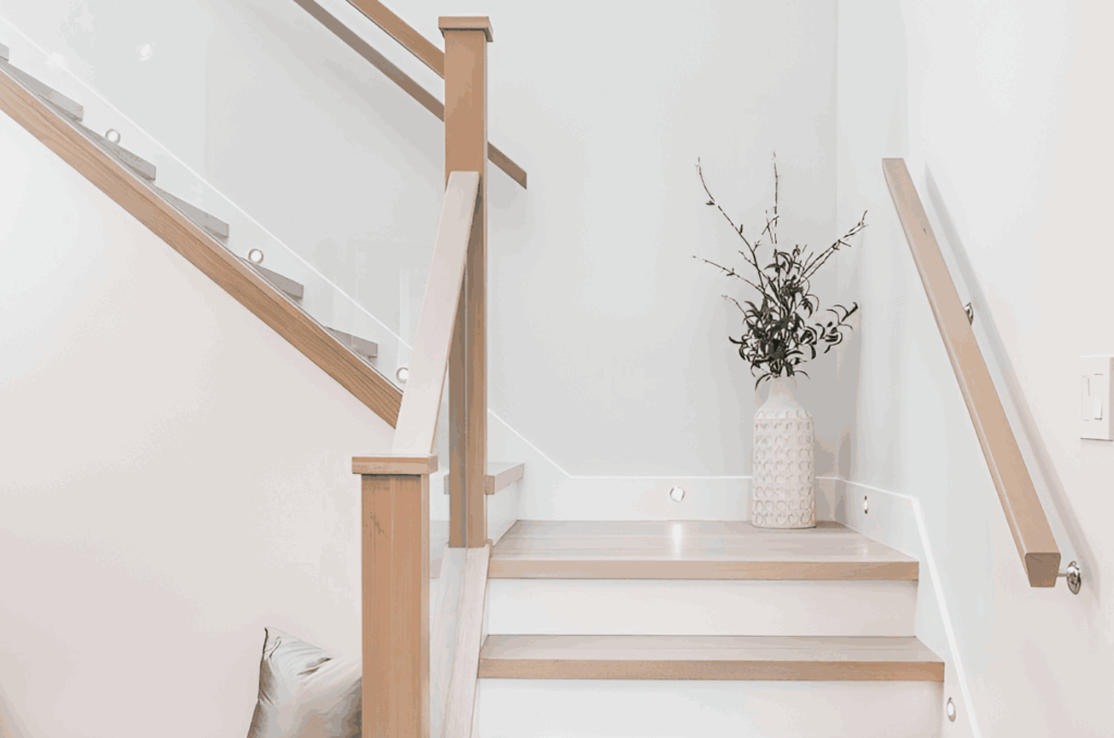 Side mounted glass railing on staircase with wood handrail, showing clean mounting details