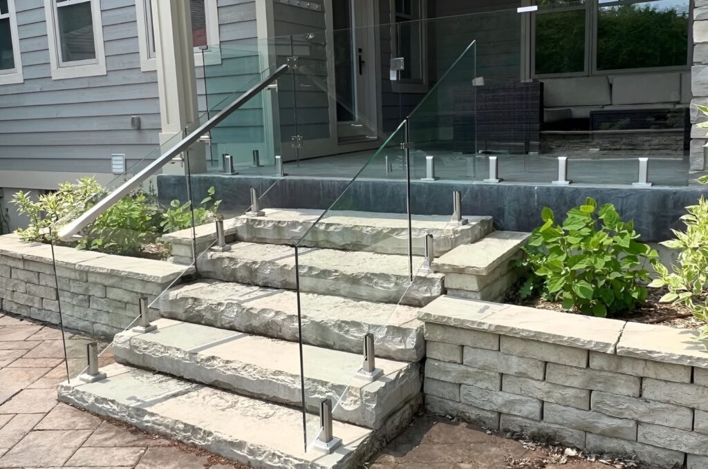 Outdoor glass railing along stone entry steps, creating a modern open look suited for Puget Sound homes