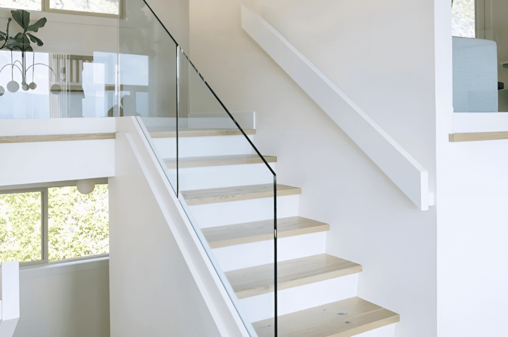 Bright white staircase with sleek glass railing that keeps the space open and airy