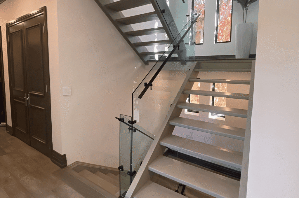 Stylish home interior staircase with glass railing and dark handrail for a modern look