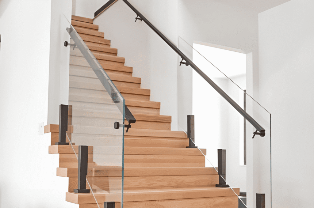 Interior design detail showing an indoor glass railing with warm wood stairs and stone accents