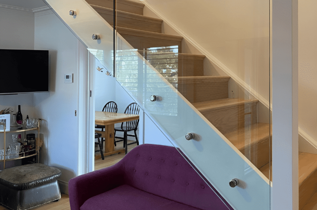 Modern glass railing systems installed along a sleek indoor staircase, creating a clean, open look in a contemporary home