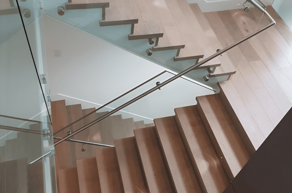 Visual of elegant indoor stair design with frameless handrail glass railings and light oak steps