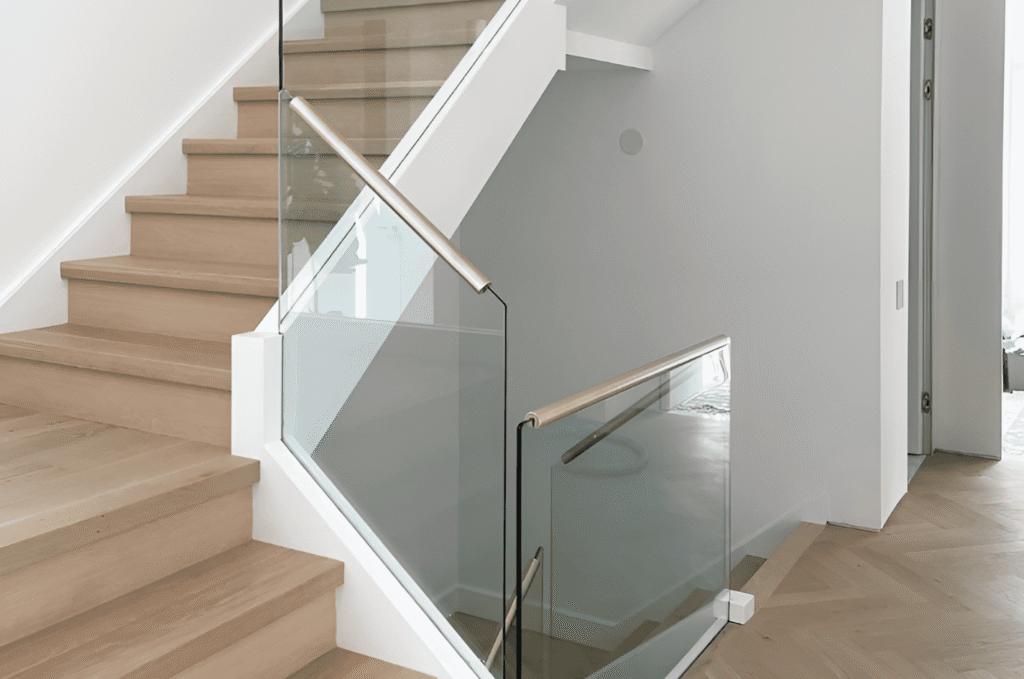 Bright hallway with wooden stairs and with transparent glass railing that enhances natural light flow