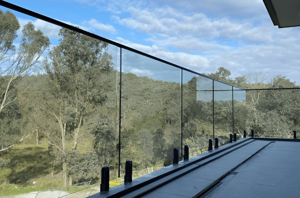 Outdoor balcony with premium glass railing systems, offering clear views of nature while maintaining safety and strength
