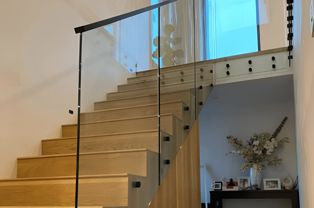 Modern wooden stairs with a clear glass stair railing, creating an open look while keeping the space safe and stylish.
