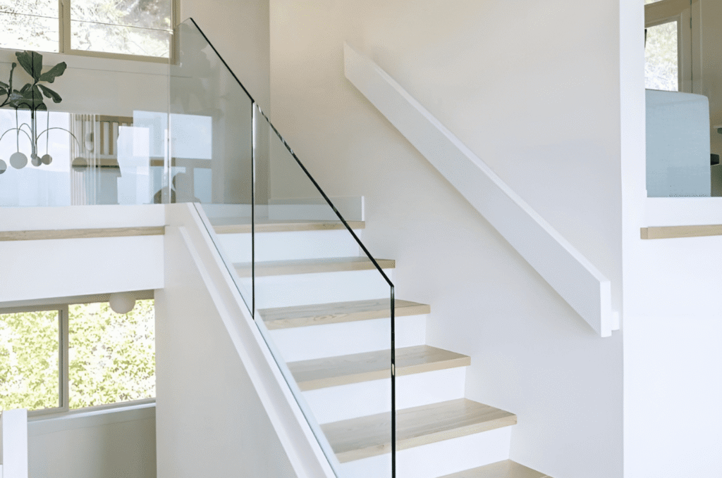 Minimalist white staircase with glass stair railing, offering a simple, clean design that fits modern home interiors.