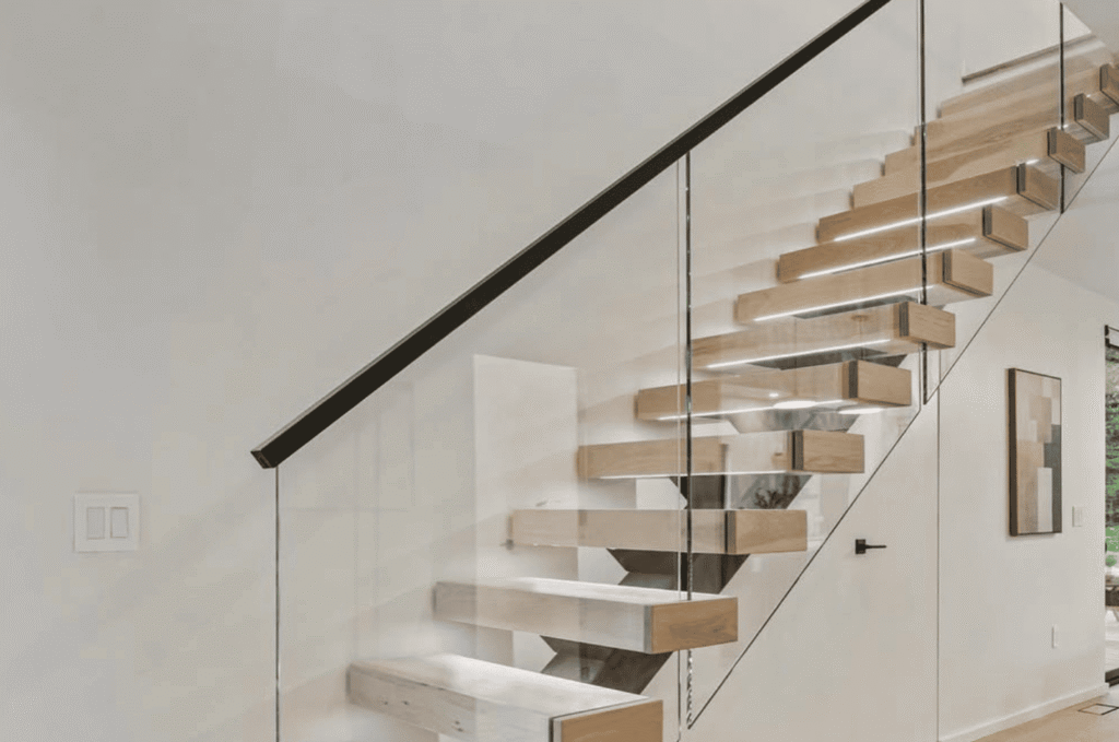 Floating stairs with glass stair railing and black handrail, designed for a clean, modern style and better light flow.