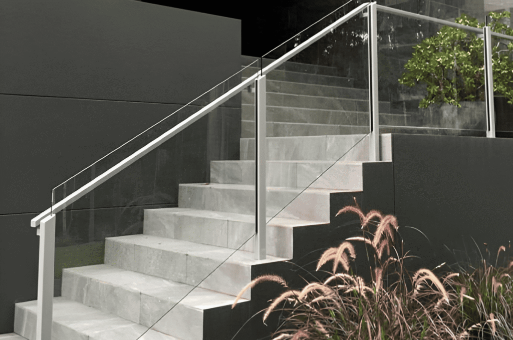 Outdoor concrete stairs with durable glass railing and metal posts for a clean, modern entrance