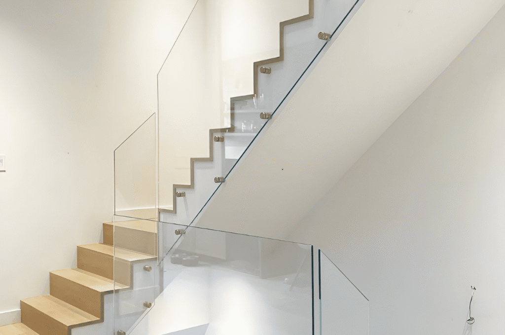 Minimalist home staircase featuring frameless glass railing panels that keep the space bright and visually open.