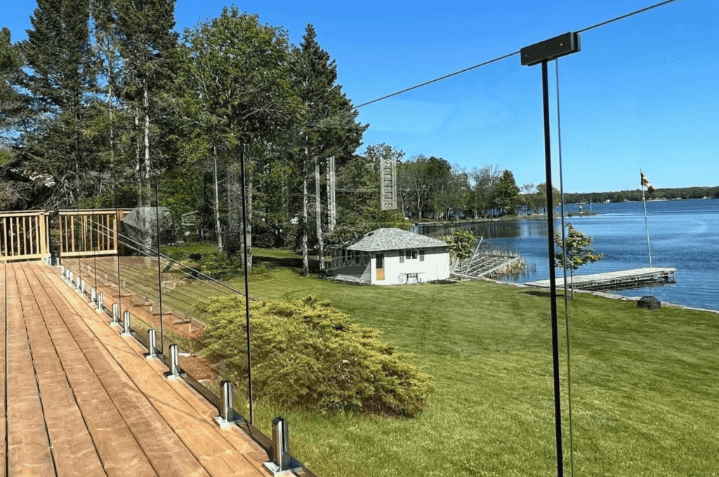 Wood deck with a clear outdoor glass railing that keeps the lake view open and unobstructed