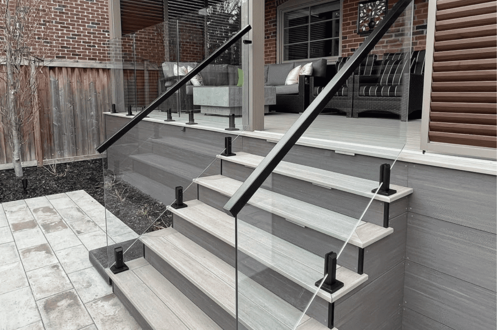 Modern home stairs with a sleek outdoor glass railing and black handrails