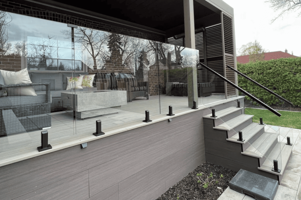 Modern patio steps with a stylish outdoor glass railing and black handrails
