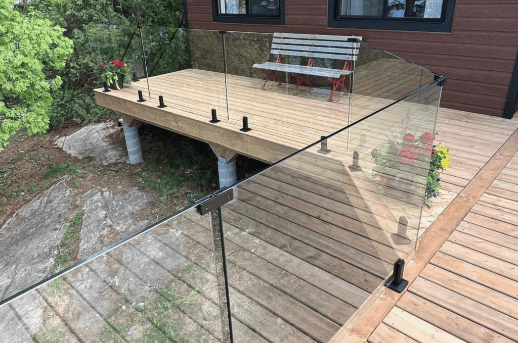 Corner view of a wooden deck protected by a clean outdoor glass railing