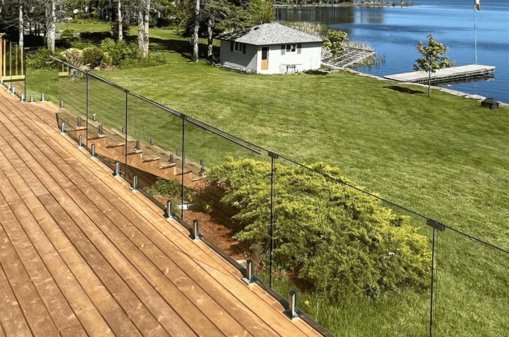 Spacious wooden deck designed with outdoor glass railing views to highlight wide waterfront views