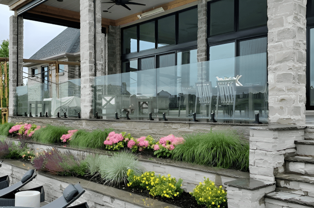 Frameless glass railing system installed with black spigot fittings between stone columns on commercial terrace