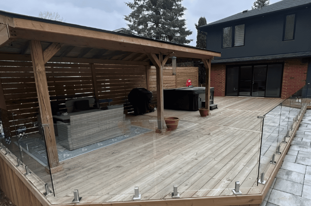 Glass deck railing with base shoe channel mounts on a wooden outdoor entertaining area ideal for choosing glass railing 
