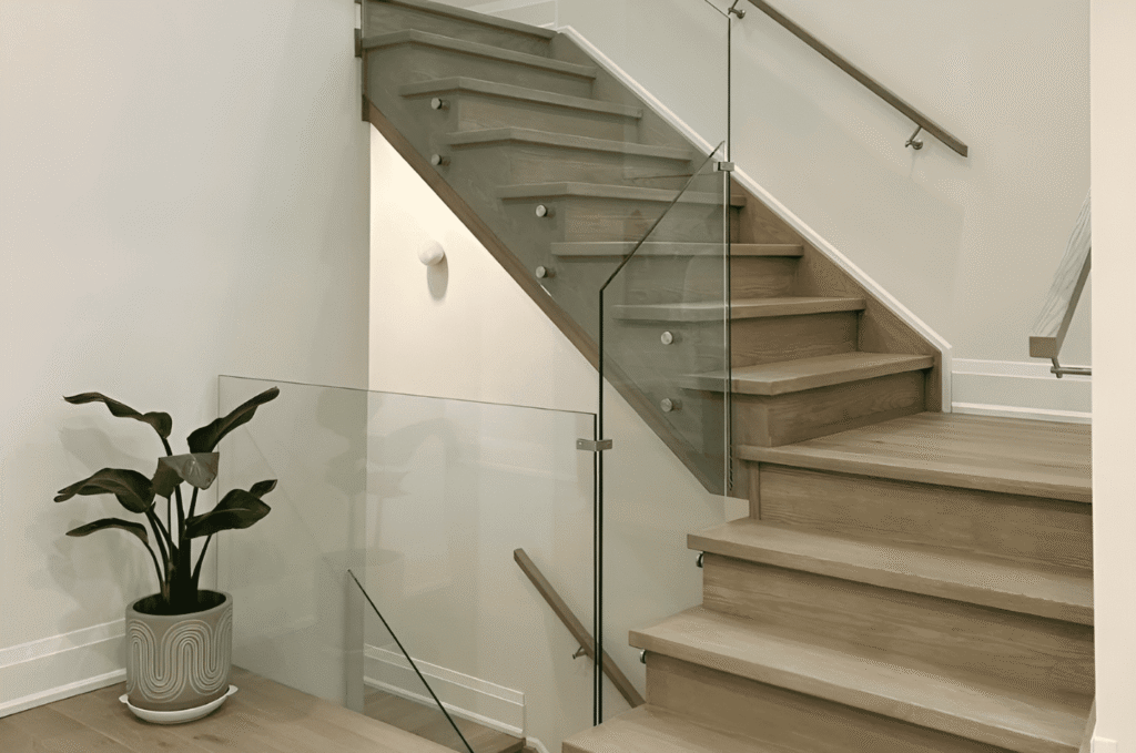 Frameless glass railing with standoff pins on a wooden staircase showing a popular glass railing choice for Seattle homes