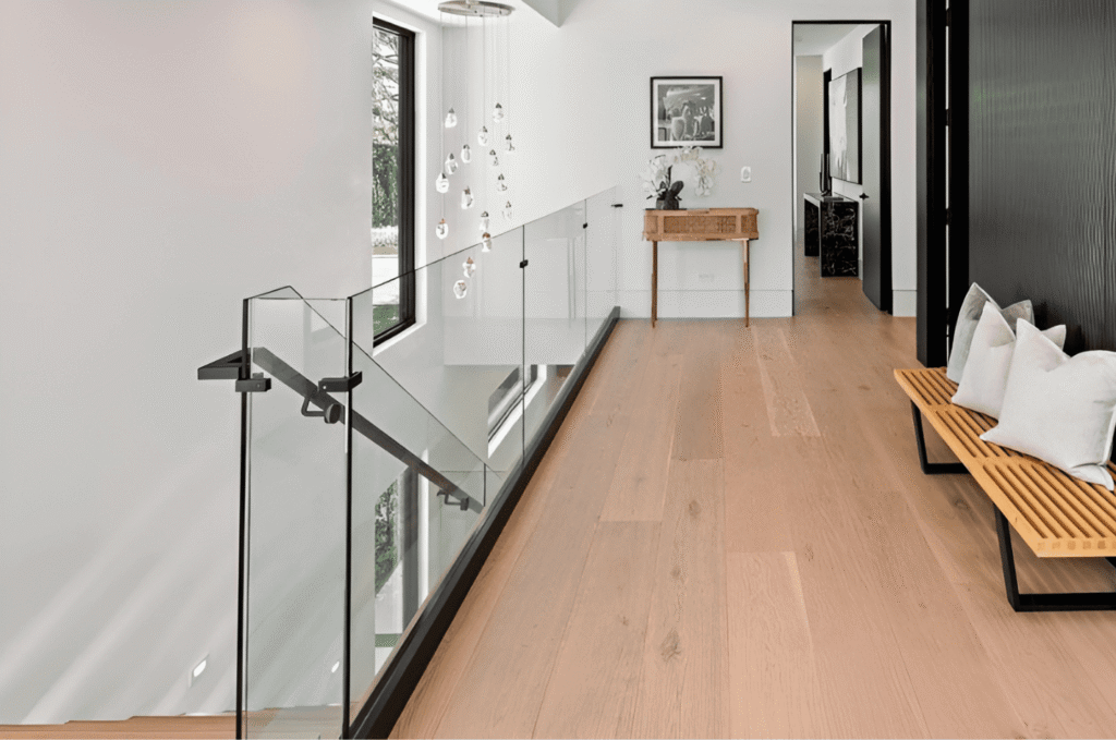 Frameless glass hallway railing with matte black base shoe channel and handrail bracket in a modern Seattle home interior.