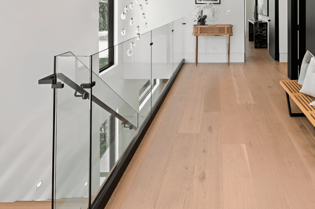 Completed glass railing timeline result showing a frameless glass stair railing with standoff mounts in a modern marble foyer