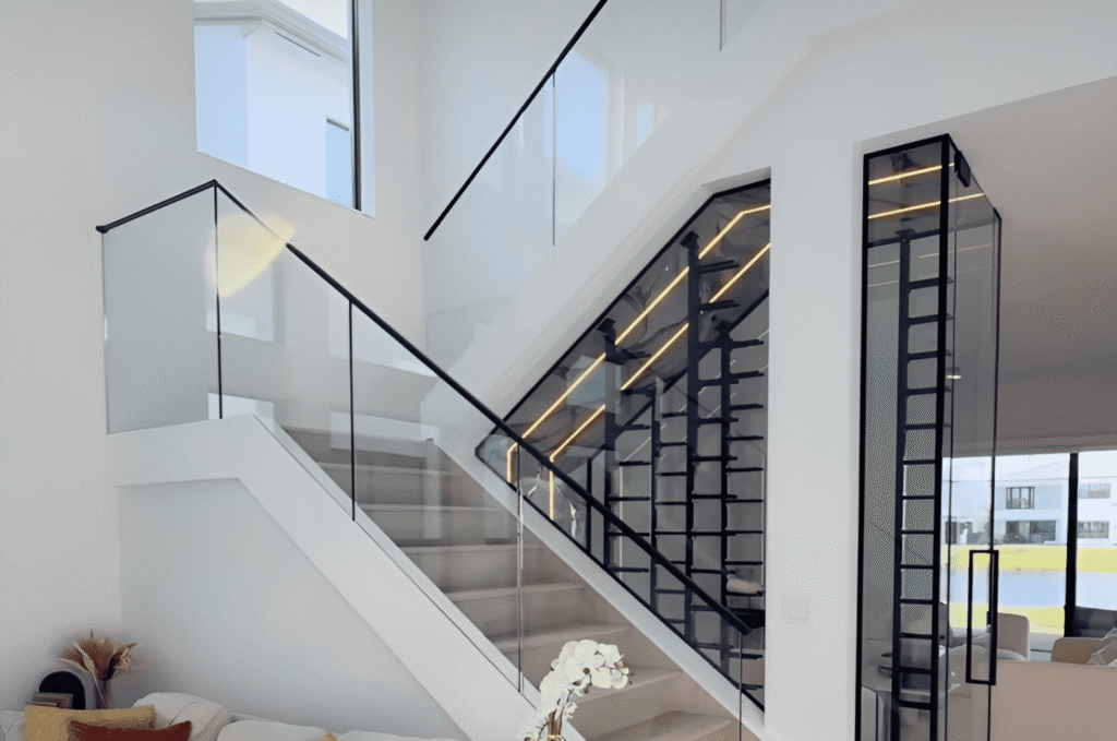 Interior glass stair railing with matte black top rail display wall in a modern Seattle home.