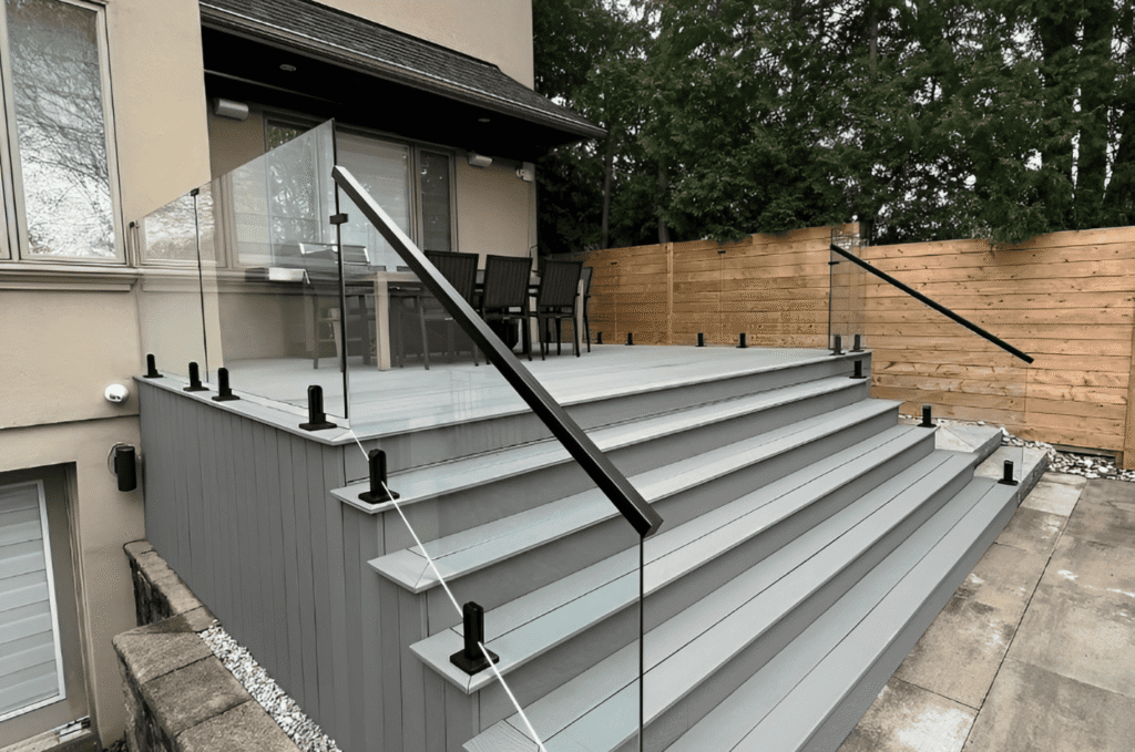 Outdoor balcony glass railing with clear panels and black posts for safe elevated deck repair checks