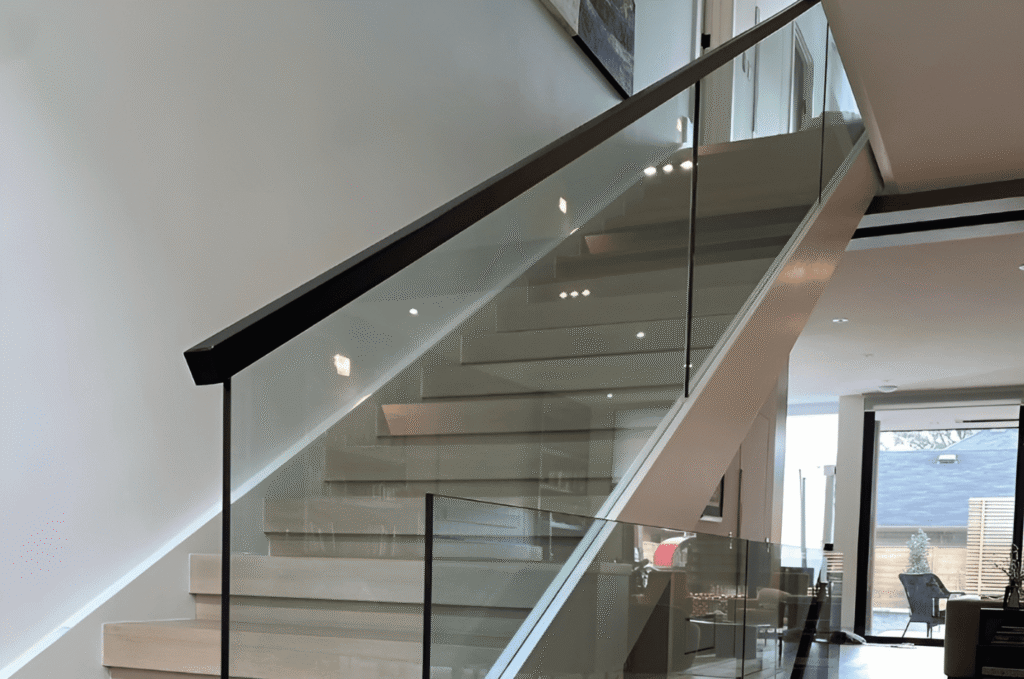 Interior glass railing installation on a modern staircase with clear panels and precise alignment before final project completion