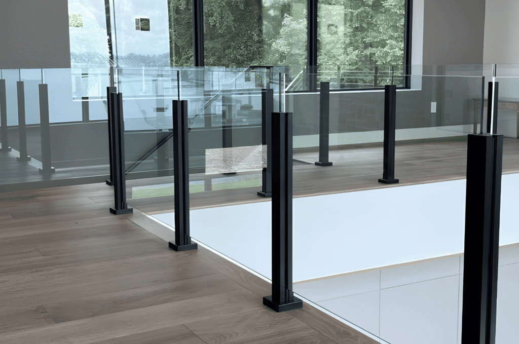 Black glass railing hardware with clear panels and open outdoor views, showing a clean modern deck-inspired railing design.