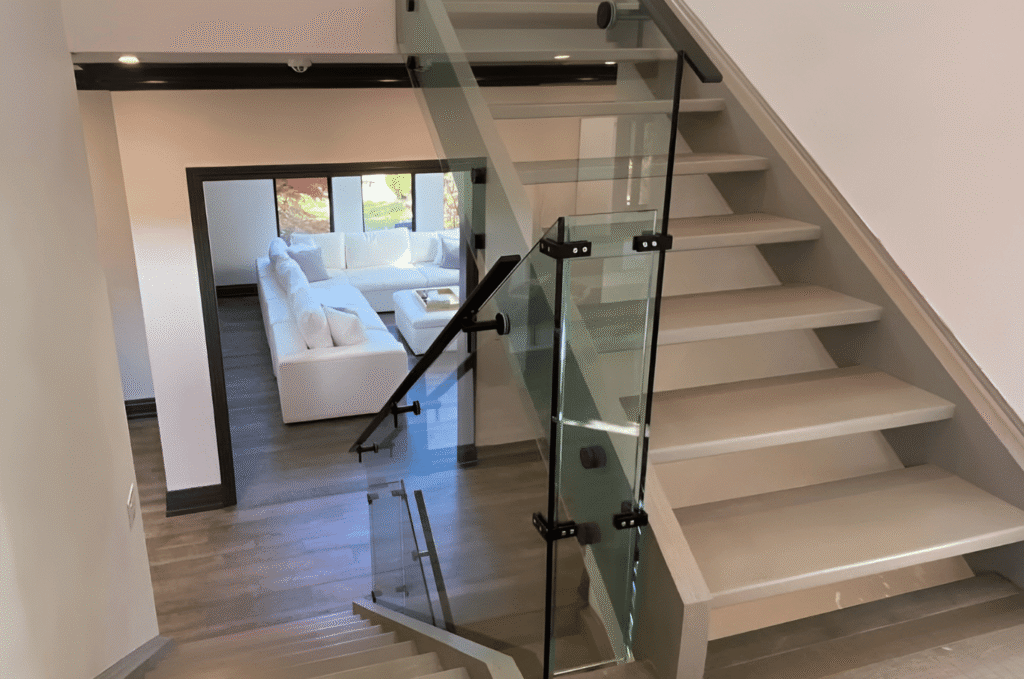 Modern glass railing installation on an indoor staircase showing clear panel layout, hardware placement, and consistent home design