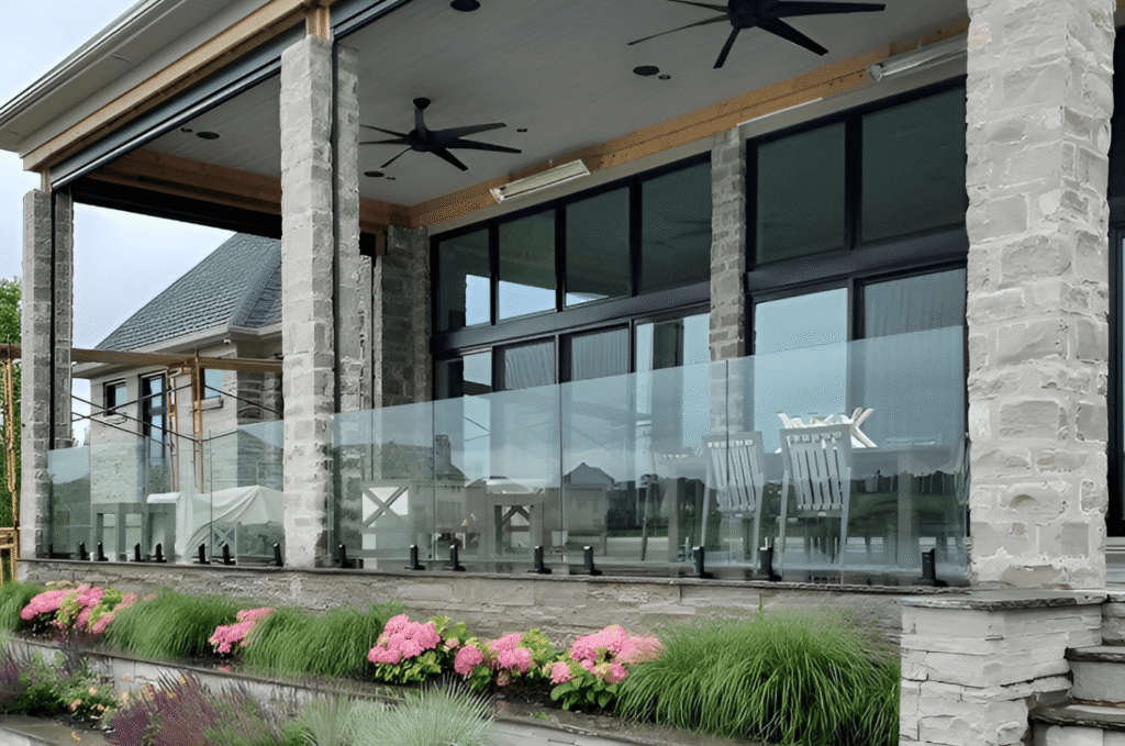 Outdoor glass railing with black base shoe hardware on stone porch and garden below needing seasonal glass railing cleaning