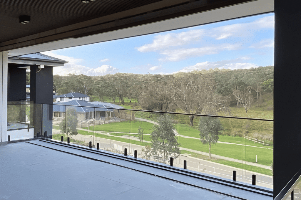 Frameless glass balcony railing with black base shoe hardware and scenic view needing winter glass railing cleaning routine