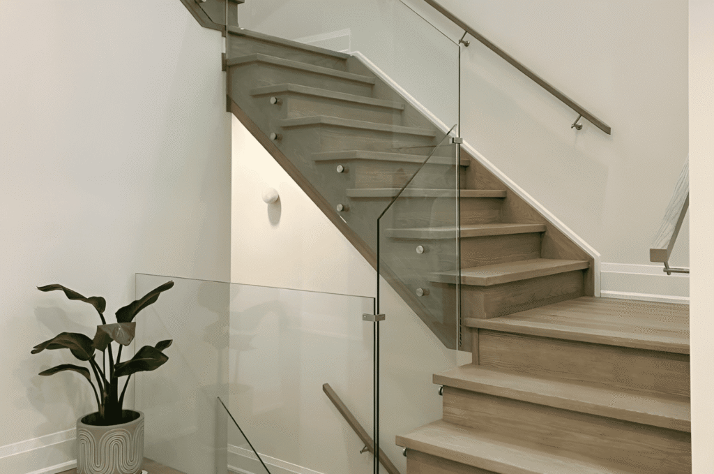 Frameless interior glass stair railing with brushed nickel hardware and oak treads in bright open plan modern home interior