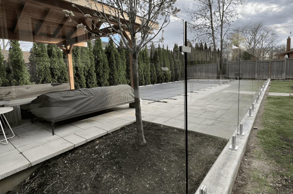 Stone retaining wall with custom glass panels and stainless spigots showing glass railing panel layout and design options