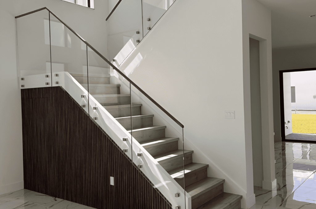 Indoor staircase with rake cut custom glass panels and standoff hardware showing tempered glass stair panel design options