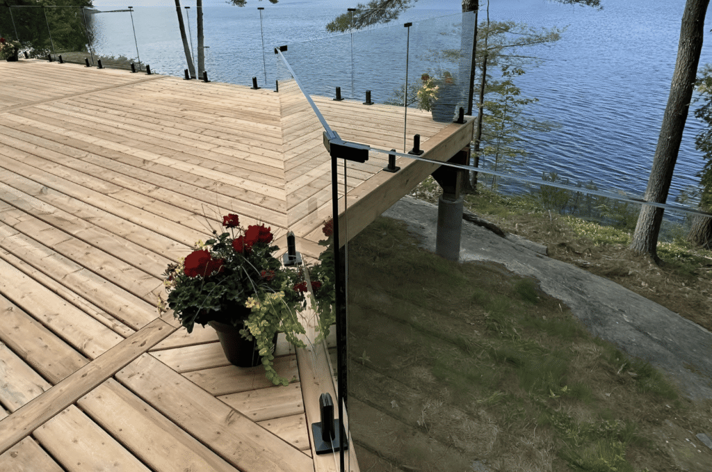 Spigot mounted glass deck railing system on wood deck with lake view showing exterior glass railing system design options