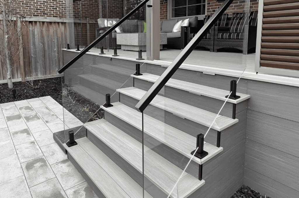 Tempered glass railing panels with black spigots along outdoor deck stairs at a modern Seattle-area home